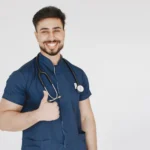 Confident male doctor in blue scrubs with a stethoscope smiling and giving a thumbs up.